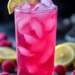 homemade Lotus-inspired energy drink with ice, pomegranate seeds, and a lemon slice garnish in a clear glass.