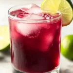 Hand pouring grape juice and ginger ale over ice in a glass