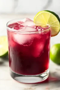 Hand pouring grape juice and ginger ale over ice in a glass