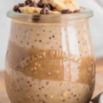 High Protein Overnight Oats layered with peanut butter, chia seeds, and berry jam in a glass jar