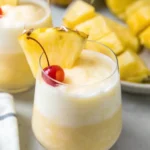 Virgin piña colada in a tall glass with pineapple wedge and cherry garnish
