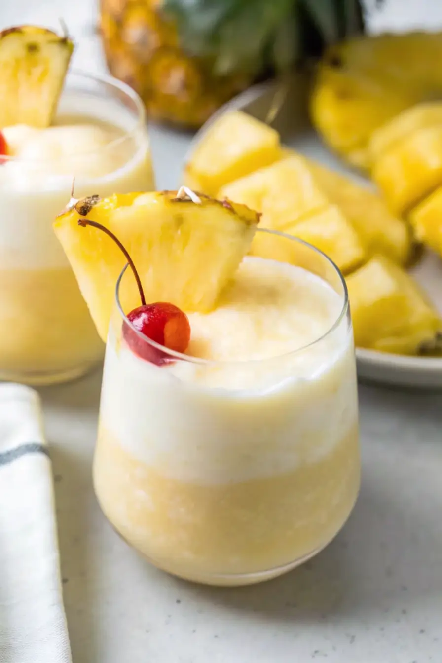 Virgin piña colada in a tall glass with pineapple wedge and cherry garnish